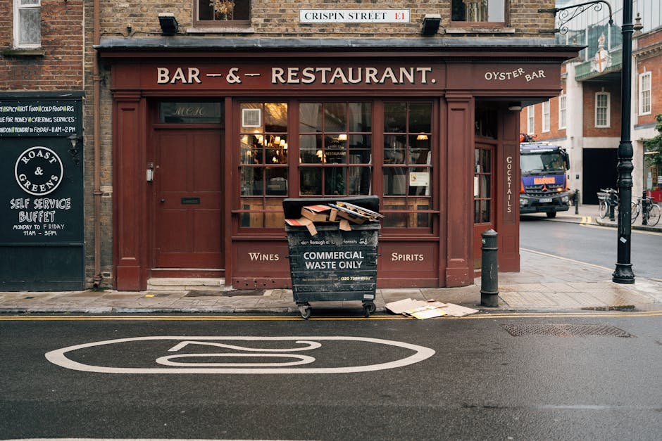 A storefront of a bar and restaurant located on Crispen Street in Kilburn, featuring a large glass window with wooden framing and a sign above reading 'Bar & Restaurant' with smaller signs indicating